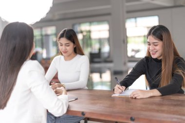Genç Asyalı üniversite öğrencileri projeyi tartışmak için bir öğretmen danışmanıyla ya da özel öğretmenle görüşüyor.
