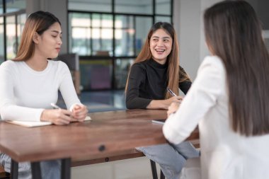 Genç Asyalı üniversite öğrencileri projeyi tartışmak için bir öğretmen danışmanıyla ya da özel öğretmenle görüşüyor.