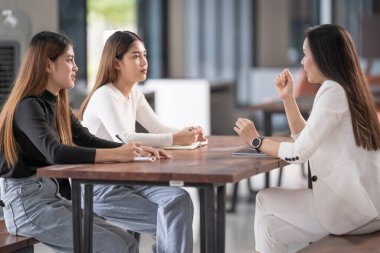 Genç Asyalı üniversite öğrencileri projeyi tartışmak için bir öğretmen danışmanıyla ya da özel öğretmenle görüşüyor.