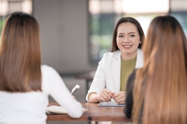 Genç Asyalı üniversite öğrencileri projeyi tartışmak için bir öğretmen danışmanıyla ya da özel öğretmenle görüşüyor.