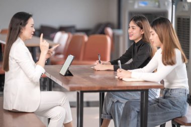 Genç Asyalı üniversite öğrencileri projeyi tartışmak için bir öğretmen danışmanıyla ya da özel öğretmenle görüşüyor.