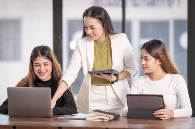 Genç Asyalı üniversite öğrencileri projeyi tartışmak için bir öğretmen danışmanıyla ya da özel öğretmenle görüşüyor.