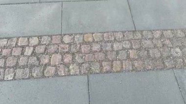 Beton ve kaldırım taşı yolu boyunca ilerliyorlar.