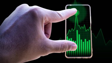 Yükselen bir yeşil borsa grafiği ve çubuk grafiğini gösteren akıllı telefonu tutan yakın plan bir el dijital çağdaki finansal büyüme yatırım başarısını, ticareti ve ekonomik analizi simgeliyor..