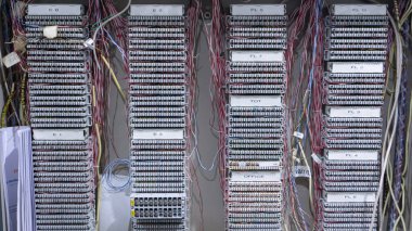 Karmaşık bir telekomünikasyon ya da telefon dağıtım çerçevesinin tam çerçeve, düzgün düzenlenmiş gri bağlantı blokları ve karışık renkli kablolarla yakın çekim görüntüsü..