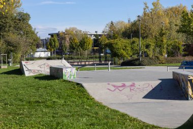 Wroclaw, Poland- 24 Ekim 2025: Beton rampalar ve grafiti sanatıyla çevrili kaykay sahası, açık hava aktiviteleri ve spor için canlı bir atmosfer sunuyor.