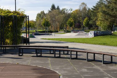 Wroclaw, Poland- 24 Ekim 2025: Beton rampalar ve banklarla çevrili kaykay parkı, kaykay ve sosyal etkileşim için canlı bir alan sunuyor