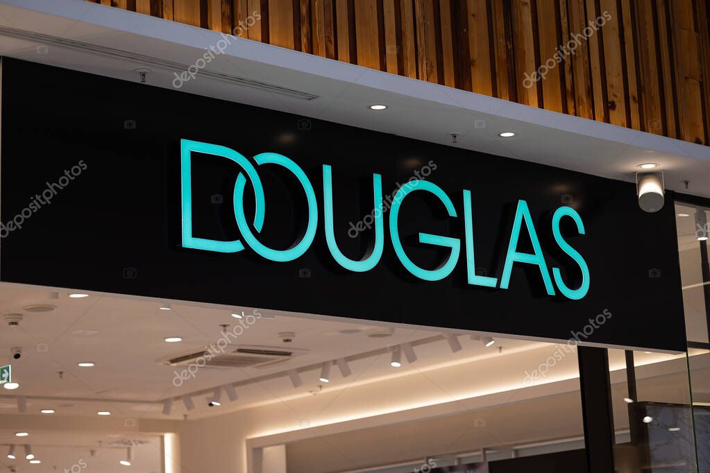 Wroclaw, Poland - October 25, 2025: Illuminated Douglas store sign glowing in turquoise lettering inside a modern shopping mall, capturing the elegant branding in a bright retail environment