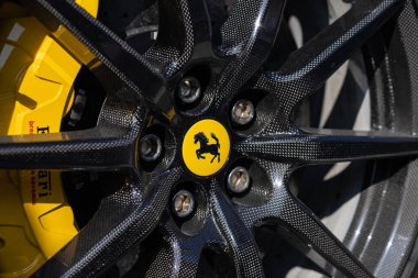 Wroclaw, Polonya - 21 Haziran 2025: Ferrari karbon fiber tekerleğinin kenarına sarı hoplayıp zıplayan at amblemi ve seramik fren ayarlı, lüks performans ve tasarım gösteren