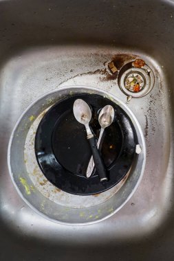 Kirli bulaşık, kaşık ve yemek artıklarıyla dolu sağlıksız bir mutfak lavabosunun yakından çekimi ev hayatı ve hijyen teması için idealdir.