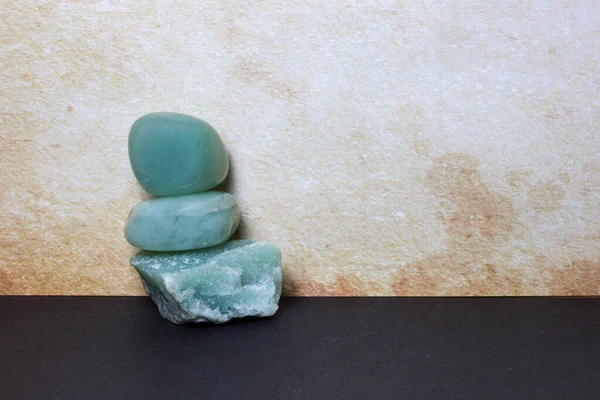 Üç yeşil Aventurine taşından oluşan dikey yığın: iki pürüzsüz yuvarlanmış kristali destekleyen ham mineral tabanı.