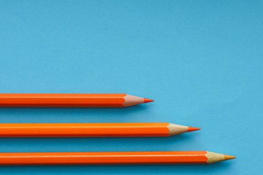 Mavi ve turuncu kalemler dinamik köşegenler halinde koyu mavi bir arkaplan üzerinde düzenlenmiş, tamamlayıcı renk kontrastını ve modern minimal tasarımı gösteren.