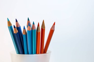 Mavi ve turuncu kalemlerin temiz stüdyo kompozisyonu tamamlayıcı renk kontrastı ve yaratıcı dengeyi sembolize eder..