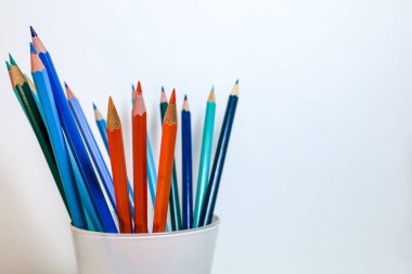 Mavi ve turuncu kalemlerin temiz stüdyo kompozisyonu krom kontrast ve yaratıcı dengeyi sembolize eder..