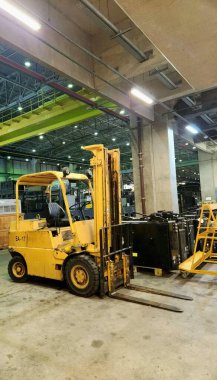 Bir bakım deposunun yan tarafından sarı bir forklift görüldü..