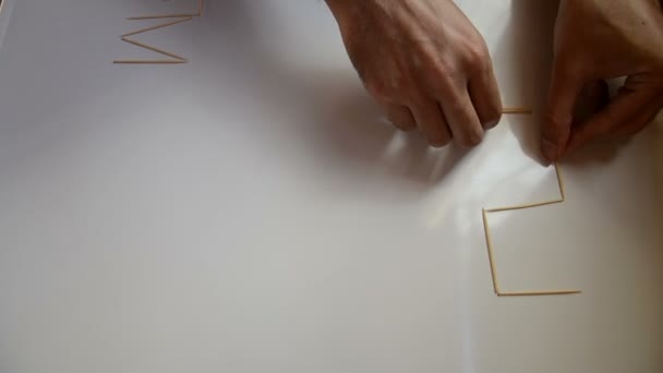 Mann zeichnet Zahnstocher Zahlen auf weißem Hintergrund — Stockvideo