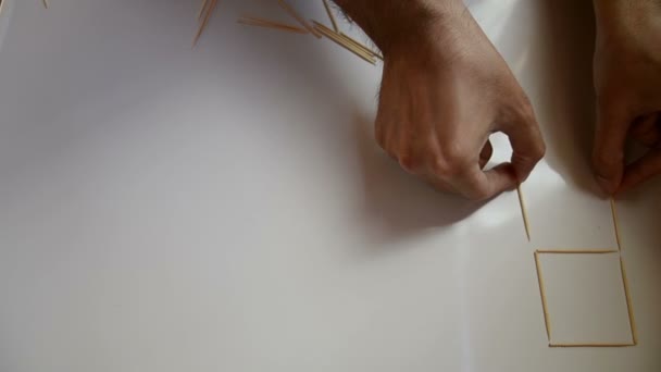 男性在白色背景上绘制牙签数字 — 图库视频影像