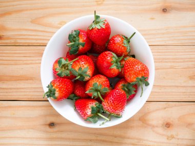 Tahta masadaki kasede taze çilekler.