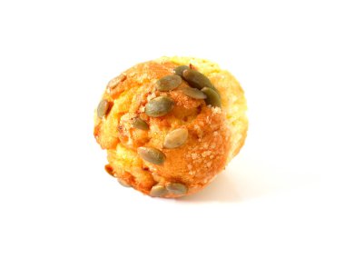 Beyaz arka planda kabak tohumlarıyla kaplı balkabaklı kek.