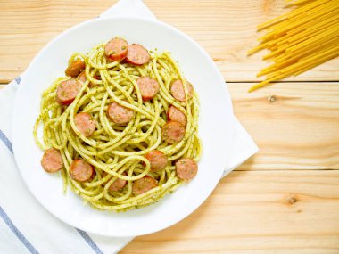 Ahşap masa üzerinde sosis ile pesto makarna