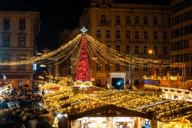 BUDAPEST, HUNGARY - 27 ARALIK. 2024: Aziz Stephen Bazilikası 'nın (Szent Istvn Bazilikası) önündeki meydanda renkli ışıklarla Noel Advent Fuarı).