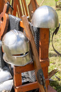 Ortaçağ çelik miğferleri ve silahları ahşap tezgahta.