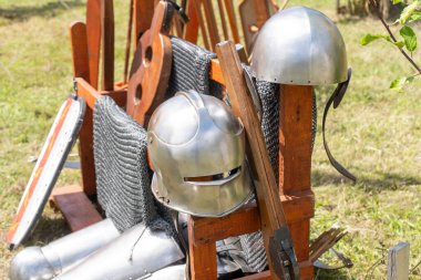 Ortaçağ çelik miğferleri ve silahları ahşap tezgahta.