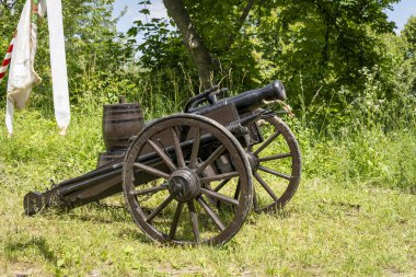 Tahta bir arabada, doğal bir arka planda barut fıçıları olan tarihi bir tarla topu.