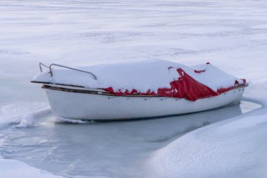Donmuş kırmızı beyaz tekne Macaristan 'ın Balaton şehrinde kışın buzlu göle demirledi.