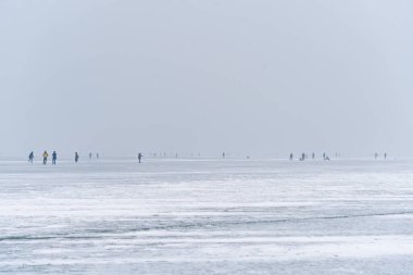 Kış sislerindeki insanlar donmuş bir gölün buzunda