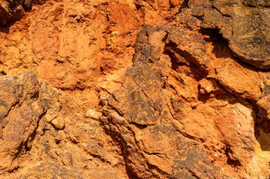Terk edilmiş bir boksit madeninde parlak turuncu renklerle erozyona uğramış bir kayalık oluşumu.