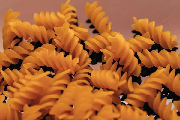 Many macaroni scattered on a black background — Stock Photo, Image