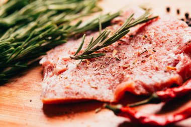 çiğ et, biberiye ve hafif ahşap bir arka plan üzerinde kırmızı acı biber fışkın