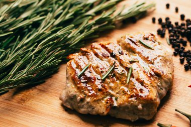 ızgara et, biberiye ve hafif ahşap bir arka plan üzerinde kırmızı acı biber fışkın