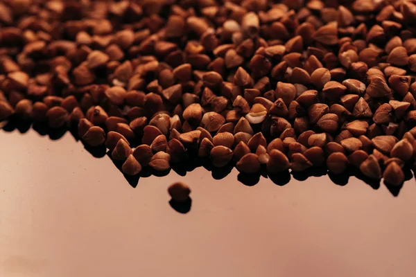 Muchos trigo sarraceno esparcidos sobre un fondo negro — Foto de Stock