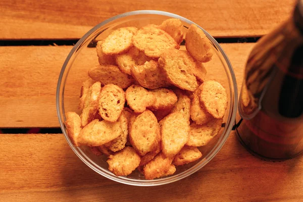 Tazón rusk con botella de cerveza marrón sobre un fondo de madera —  Fotos de Stock