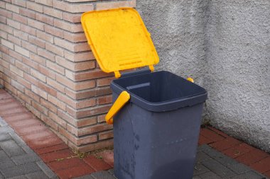 Evin yanında sarı kapaklı siyah çöp kutusu. İtalya 'da küçük bir köyde atık yönetimi. Atık toplama, onu yeşil enerji ve gübre haline getirmek için. Çevre koruması.