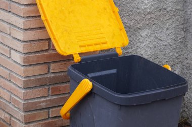 Evin yanında sarı kapaklı siyah çöp kutusu. İtalya 'da küçük bir köyde atık yönetimi. Atık toplama, onu yeşil enerji ve gübre haline getirmek için. Çevre koruması.