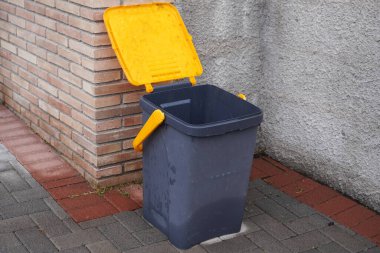 Evin yanında sarı kapaklı siyah çöp kutusu. İtalya 'da küçük bir köyde atık yönetimi. Atık toplama, onu yeşil enerji ve gübre haline getirmek için. Çevre koruması.
