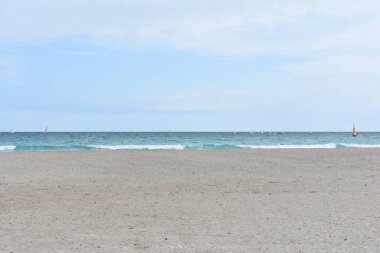 İlkbaharda Poetto plajı, Cagliari, Sardinya, İtalya. Uçurtma alıştırması yapan insanlar. Renkli uçurtmalar. Su sporları. Sardegna 'da tatiller. İtalya 'ya git. Seyahat ve turizm konsepti. Akdeniz 'de. Beyaz kumlu sahil.