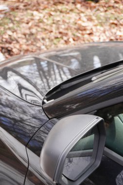 Arabanın yan aynasına yakın çekim. Park edilmiş araba. Arabayla yolculuk. Siyah otomobil, yakın görüntü, kırpılmış resim.