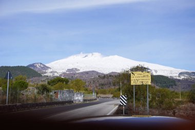 Kışın Etna volkanı. Yürüyüş alanı. Volkanik Etna Dağı manzarası karlı, güneşli bir günde bitki örtüsü, Catania, Sicilya, İtalya. Etna 'da yol işaretleri ve park halindeki bir arabayla ıssız bir yol..