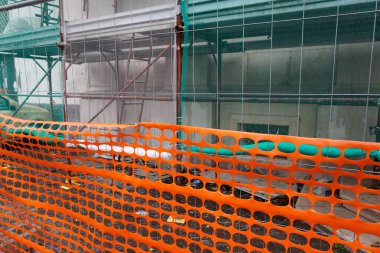 İnşaat ve güvenli turuncu plastik ağ çitleri için yapı iskelesi. İnşaat halindeki yapı iskelesi olan bir bina. İnşaat çalışmalarına güvenli erişim için Sorrento, Campagna, İtalya 'daki konut geliştirme iskelesi.