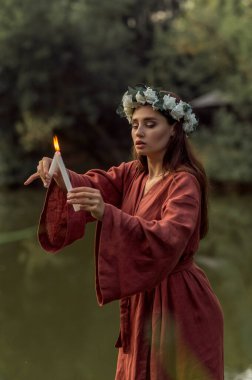 Boho tarzı: terracotta keten tunik ve iskelede mum yakan çelenk içinde ince bir model. Doğayla uyum, organik estetik