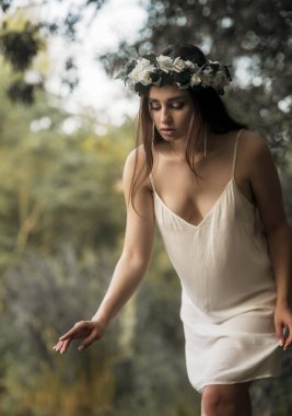 Beyaz cüppeli ve çiçekli bir kadın. Suya ve antik ayinlere ruhsal bağlılık kavramı. Yaz ortası ya da gün dönümü kutlama havası.