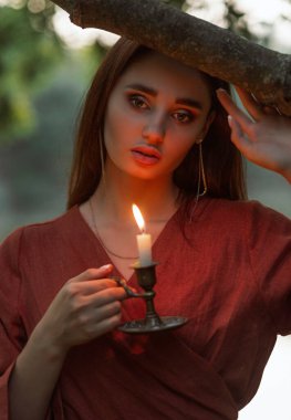 Sıcak mum ışığında kadınların karanlığa karşı yüzlerini şekillendirdikleri dramatik yakın plan portre. Gizem, yalnızlık ve akşamları ışığın rahatlatıcı gücü kavramı..