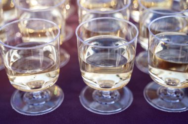 Bardakları, parlak sabah güneşiyle aydınlatılan bir masada şarapla kapat. Rafine yemek, altın saat estetiği ve alkollü içecek fotoğrafçılığı kavramı..