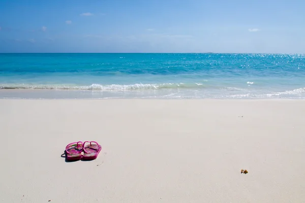 Paar farbige Sandalen an einem weißen Sandstrand — Stockfoto