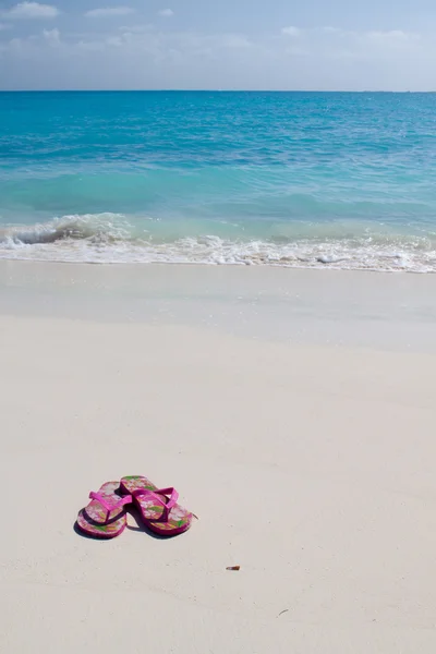 Par de sandalias de colores en una playa de arena blanca —  Fotos de Stock