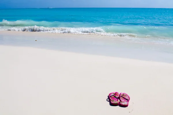 Pair of colored sandals on a white sand beach — Stock Photo, Image